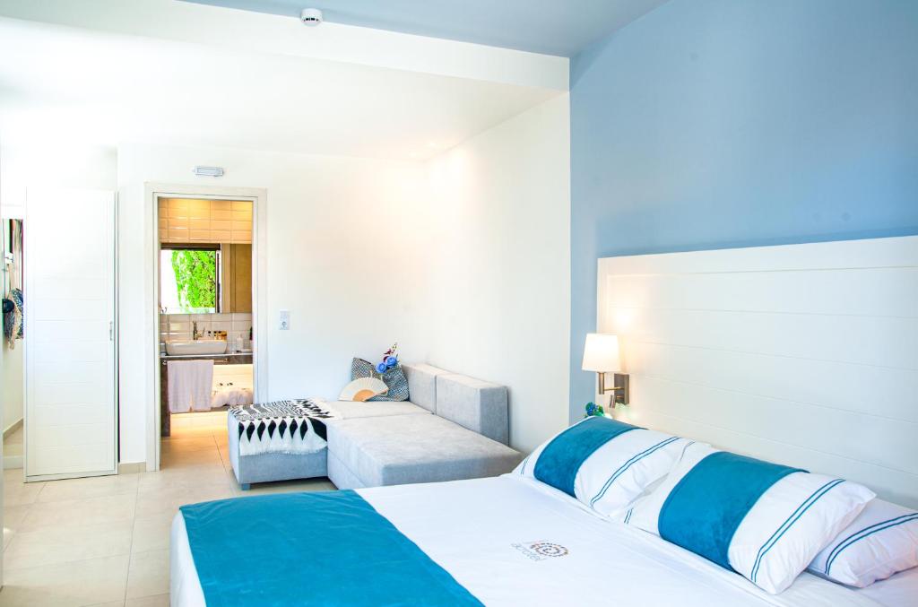 a bedroom with two beds and a couch in it at Acrotel Lily Ann Village in Nikiti