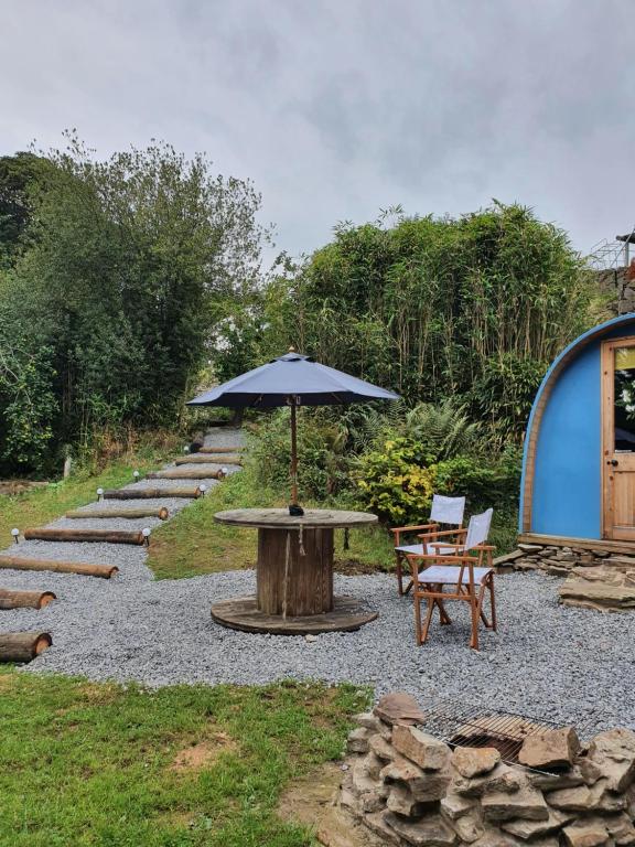 eine Terrasse mit einem Sonnenschirm, einem Tisch und Stühlen in der Unterkunft Gower Pods in Penclawdd