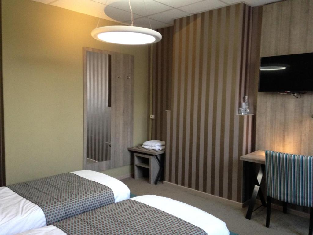a hotel room with two beds and a table at Hotel Mille Colonnes in Leuven