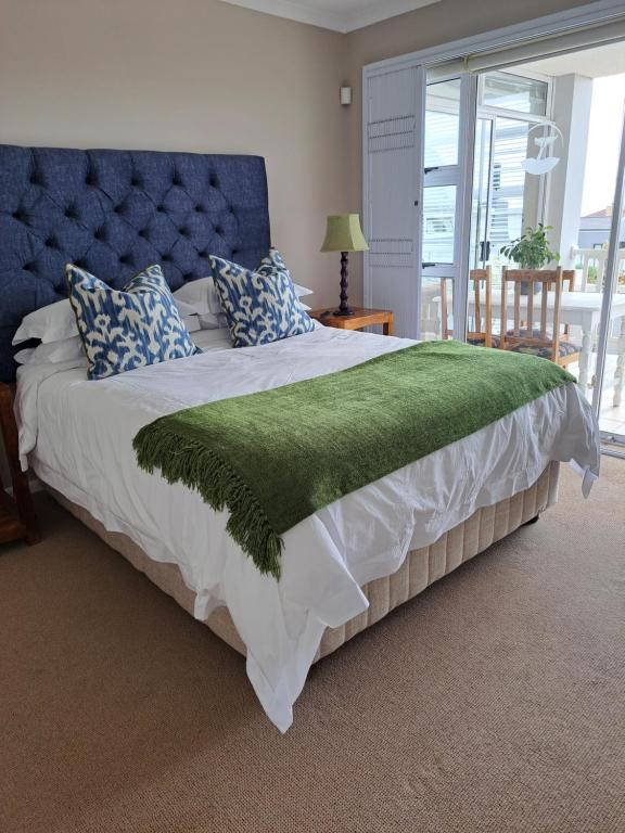 Un dormitorio con una cama grande con una manta verde. en Bay Haven, en Gansbaai