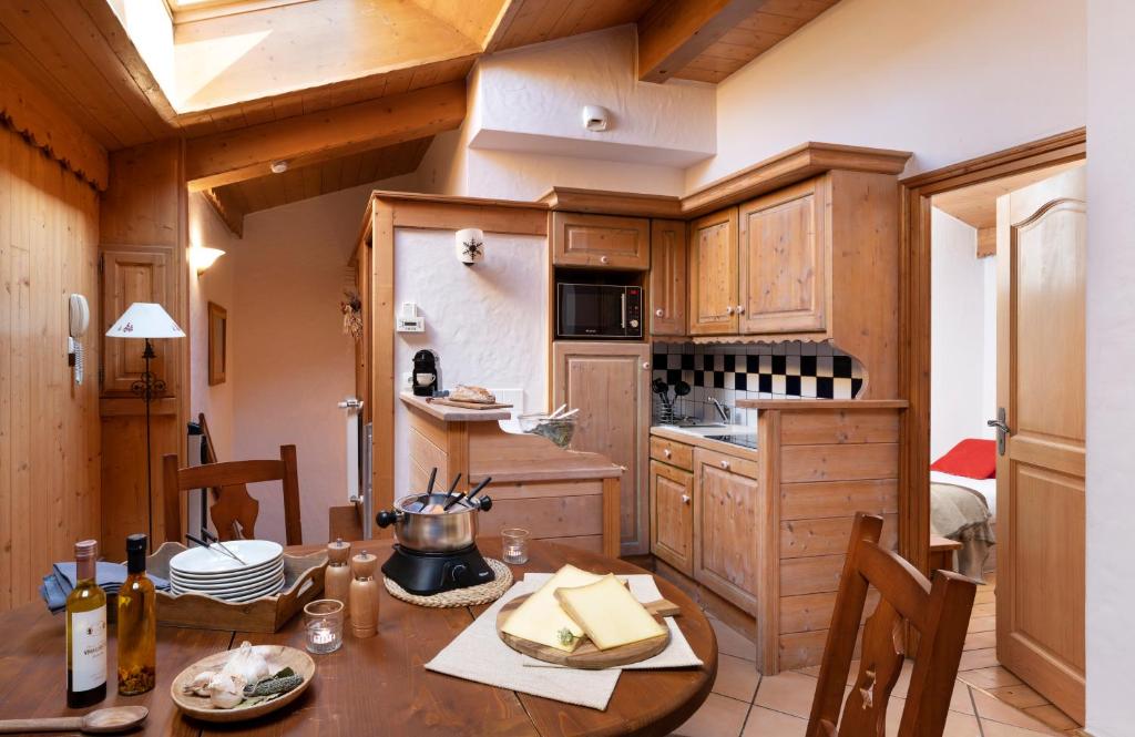 a kitchen with wooden cabinets and a wooden table at Résidence Pierre &amp; Vacances Premium Les Alpages de Chantel in Arc 1800