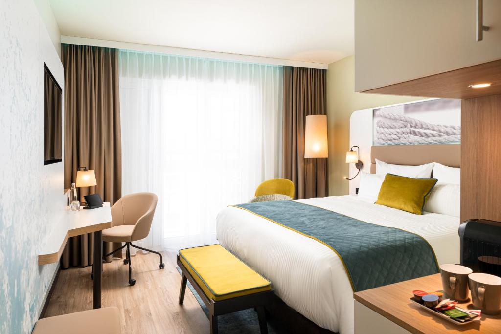 Habitación de hotel con cama y escritorio en Leonardo Hotel Hamburg Altona, en Hamburgo