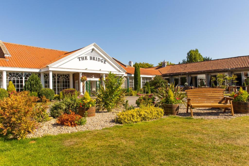 un edificio con un banco de madera en el patio en The Bridge Hotel and Spa, en Wetherby