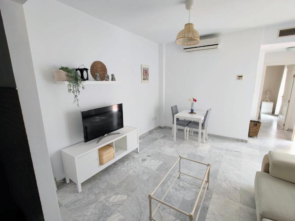 - un salon blanc avec une télévision et une table dans l'établissement Apartamento para dos en San Bernardo, à Séville