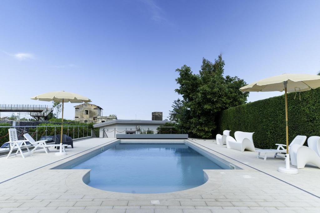 - une piscine avec des chaises et des parasols blancs dans l'établissement Tropical House, à San Leonardello