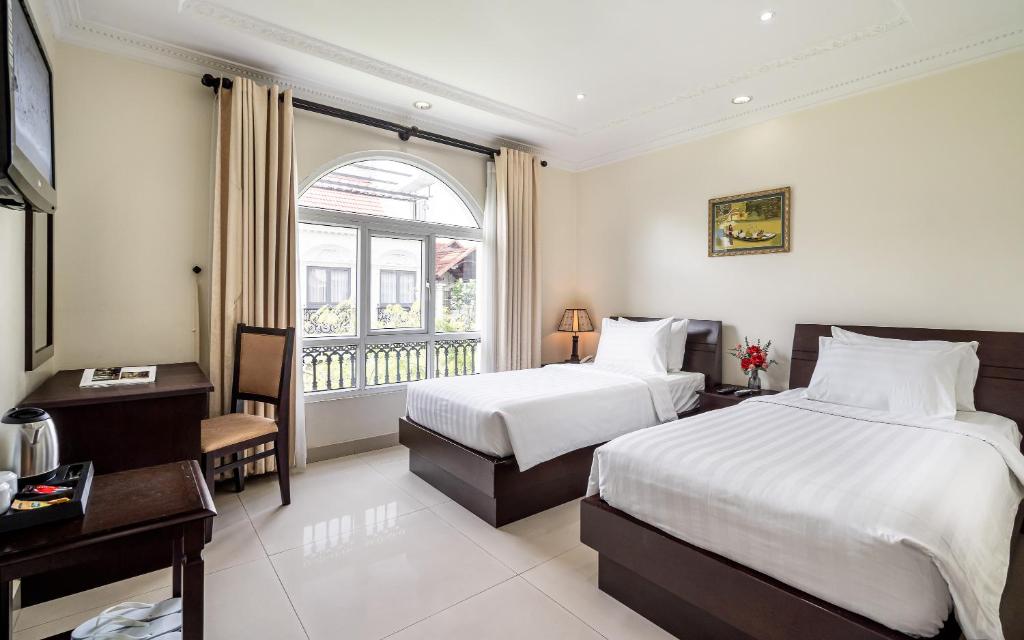 a hotel room with two beds and a window at La Bonita Hotel and Apartments in Ho Chi Minh City