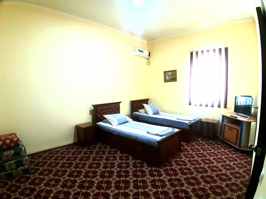 a hotel room with two beds and a window at Khiva Indi Guest House in Khiva