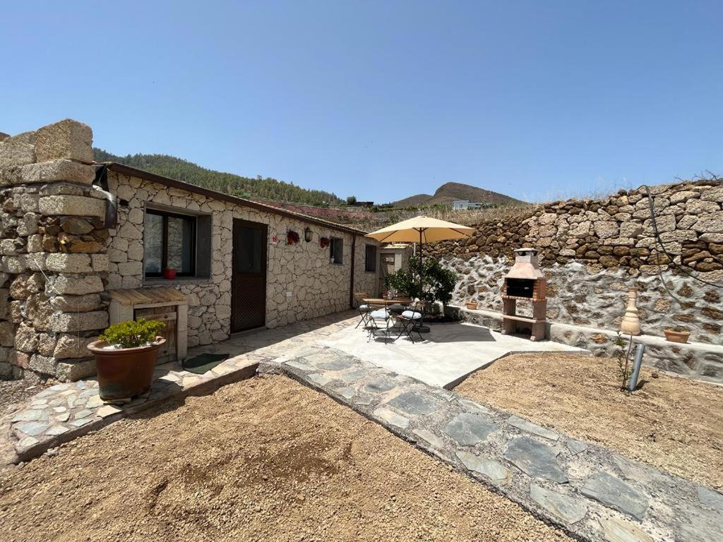 ein Steingebäude mit einer Terrasse mit einem Sonnenschirm in der Unterkunft Casa Luis Pico in Granadilla de Abona