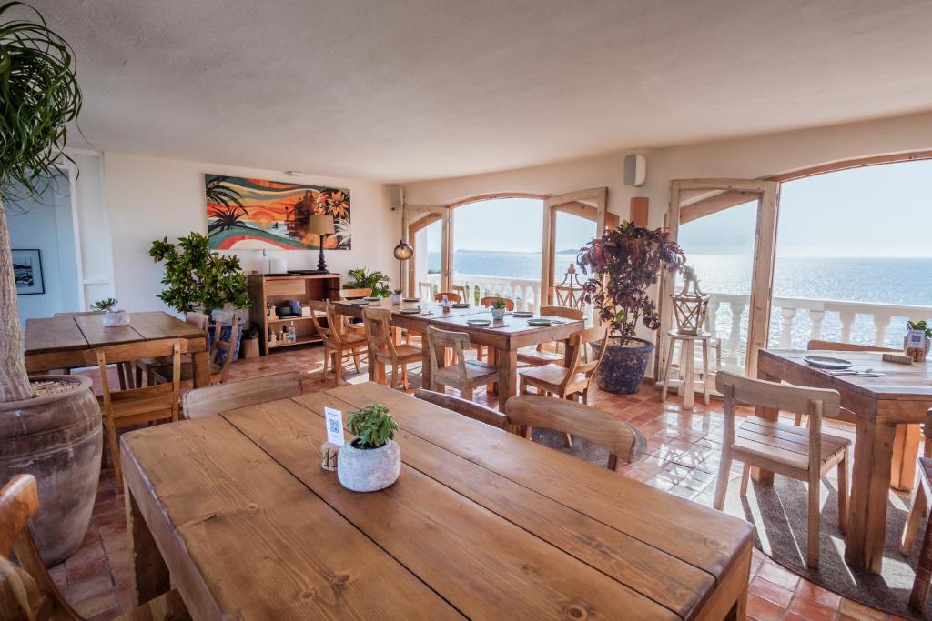 a restaurant with wooden tables and chairs and the ocean at Hostal La Torre Ibiza Cap Negret in San Antonio