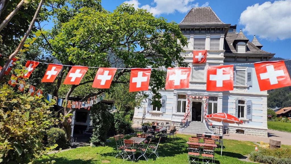 an old house with red and white flags in front of it at Adventure Hostel Interlaken in Interlaken