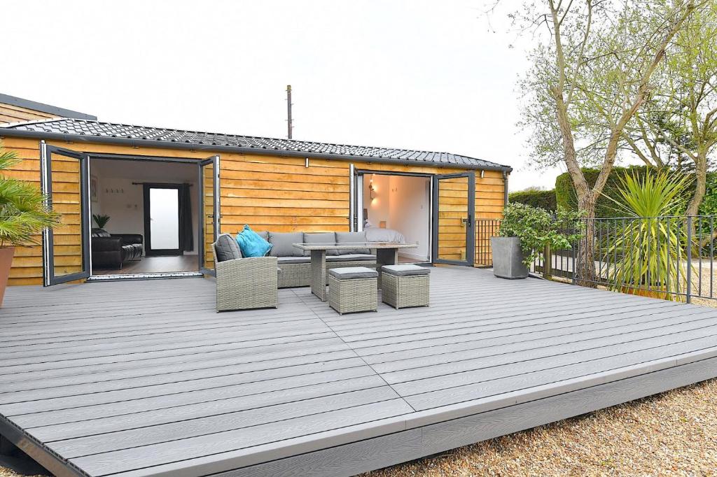 a wooden deck with a couch and a table at Cheerful 1BD Cottage with Parking Nr Guildford in Guildford