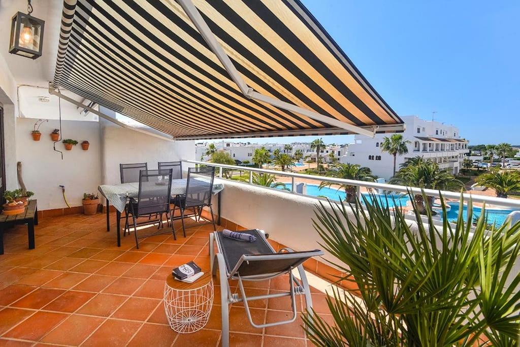 balcón con mesa, sillas y piscina en LAS CALAS Nice apartment near the sea., en Portopetro