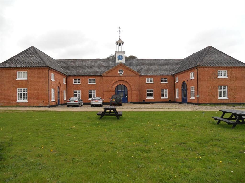 a large brick building with two picnic tables in front of it at The Stables at Henham Park in Southwold