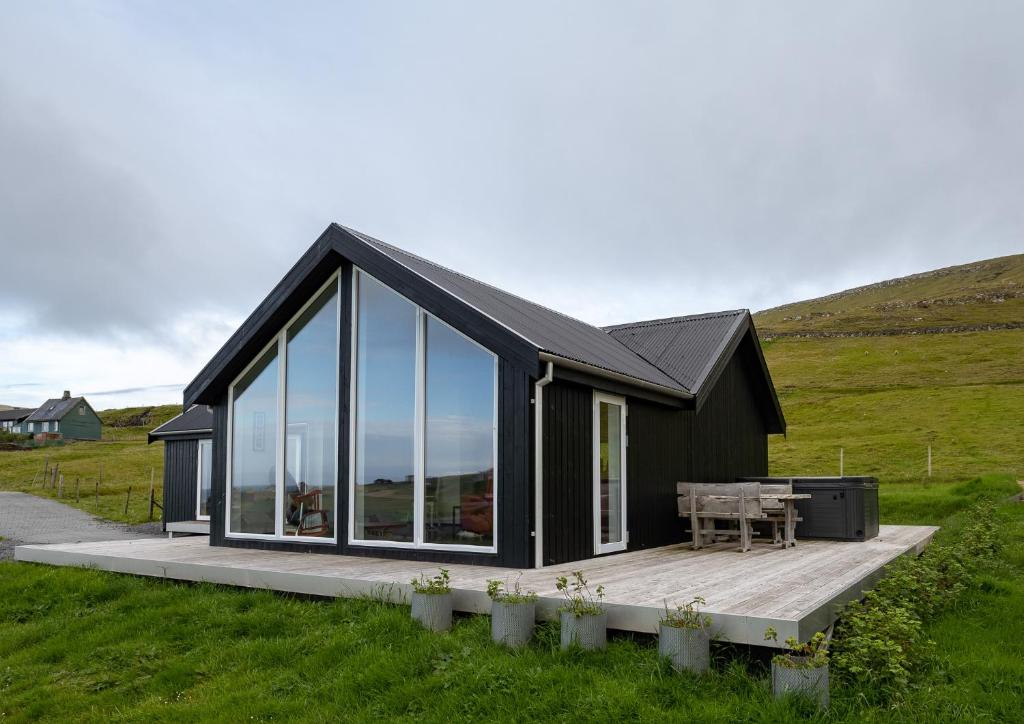 a black house with glass windows and a wooden deck at Luxurious cabin / 3 BR / Scenic village in Skálavík