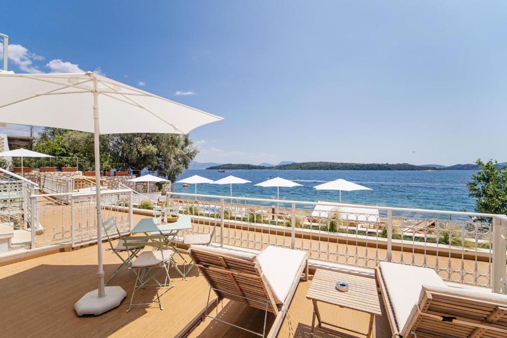 una terraza con sillas y sombrillas y el océano en Greek Beach House A2 Lefkada, en Nydri