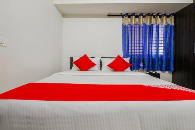 a bedroom with a large white bed with red pillows at Honey Residency Airport Codissia stay in Coimbatore