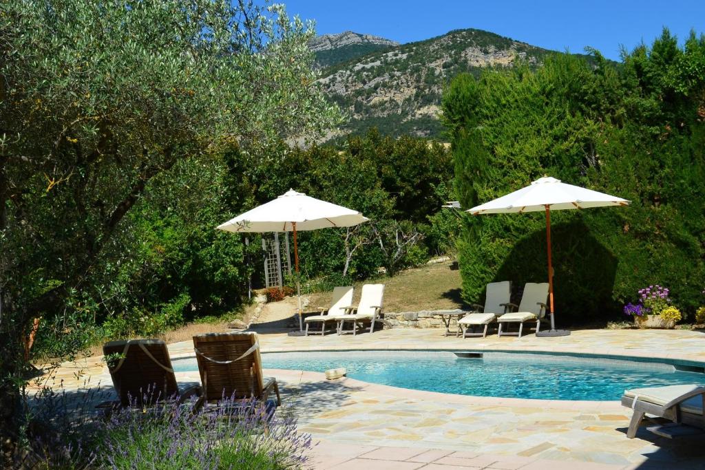 a swimming pool with two umbrellas and chairs at Hameau d'hôtes La Roseraie-Drôme in Condorcet