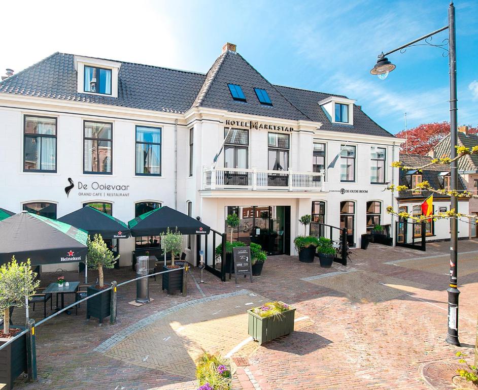 a large white building with a courtyard in front of it at Hotel Marktstad in Schagen
