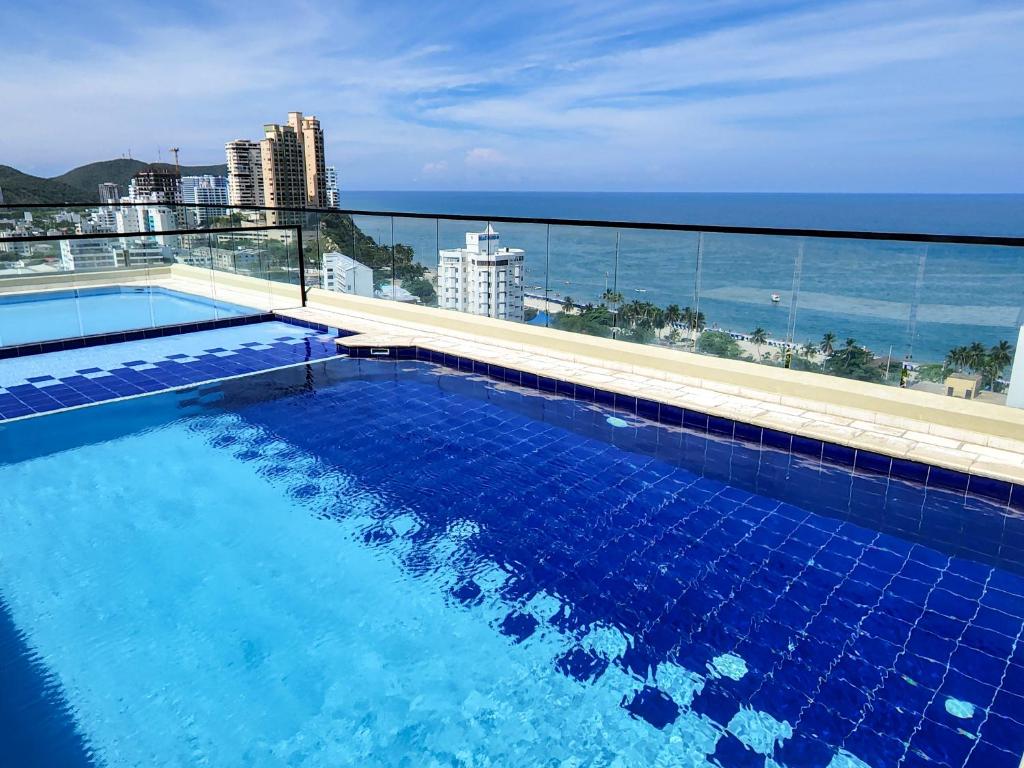 a swimming pool on top of a building with the ocean at Apartasuites VITA 945 RODADERO - By Bedviajes in Santa Marta