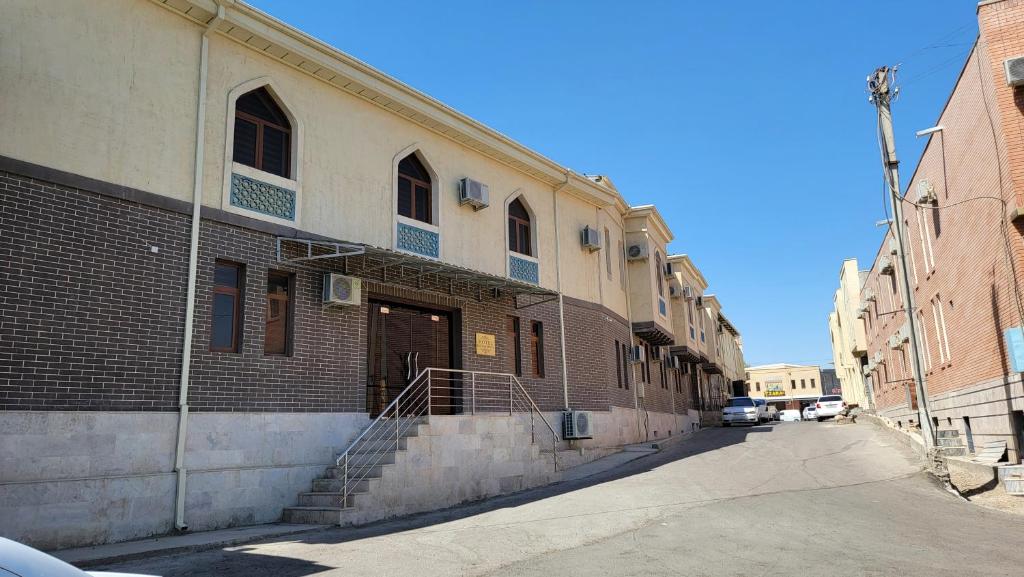 a brick building with a staircase on the side of a street at MELODIA Guest House in Bukhara