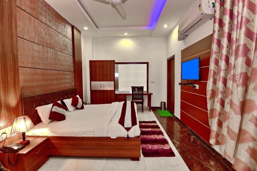 a bedroom with a bed and a desk and a table at Kartikay hotel in Hisār