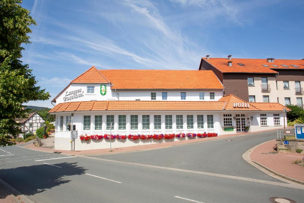 a large white building with an orange roof on a street at Lampes Posthotel in Grünenplan