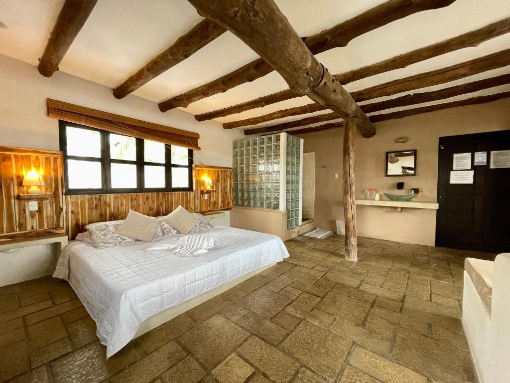 een slaapkamer met een groot bed in een kamer met houten plafonds bij Johnnys Place Hotel in Monterrico