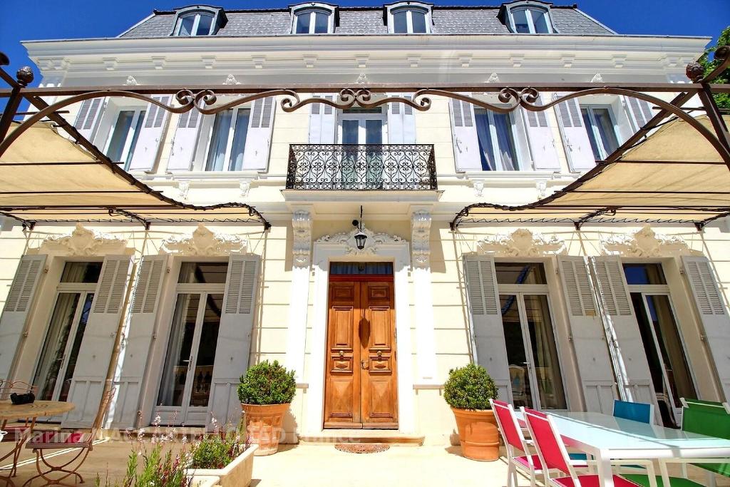 uma casa branca com uma mesa e cadeiras em frente em Manoir d'Amaury - Chambres d'hôtes em Gréoux-les-Bains