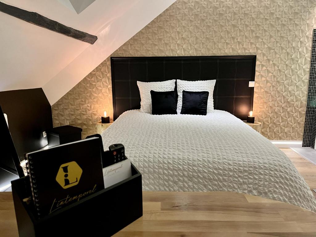 a bedroom with a large bed with a black headboard at L'Intemporel Suite Spa in Champagne-sur-Oise
