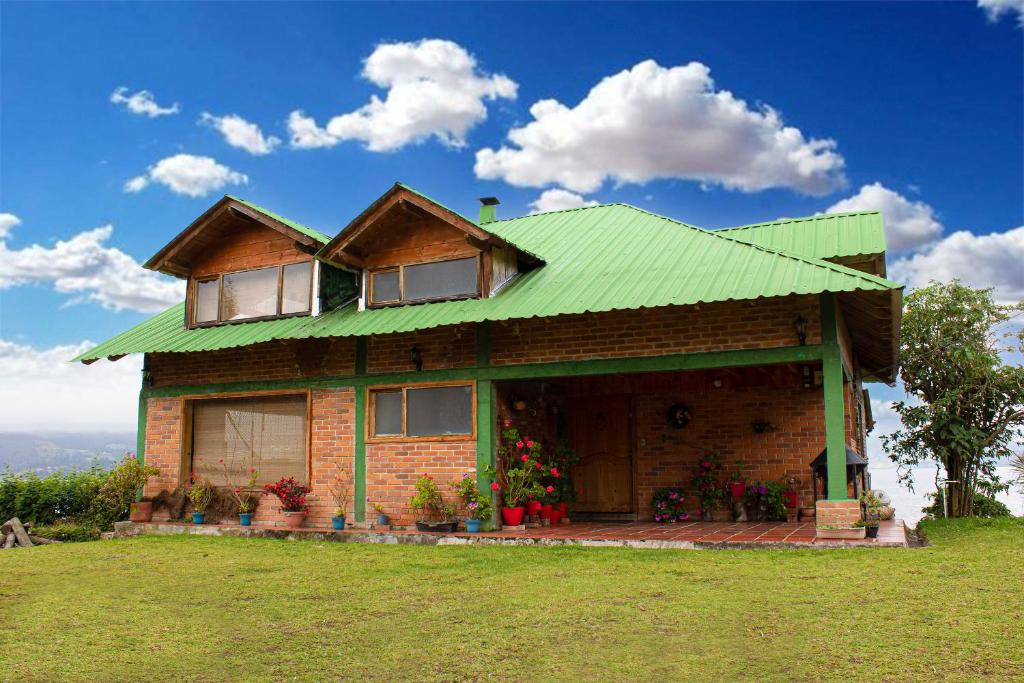 a house with a green roof on a field at Cabaña en La Cocha - Janaxpacha in Los Alisales