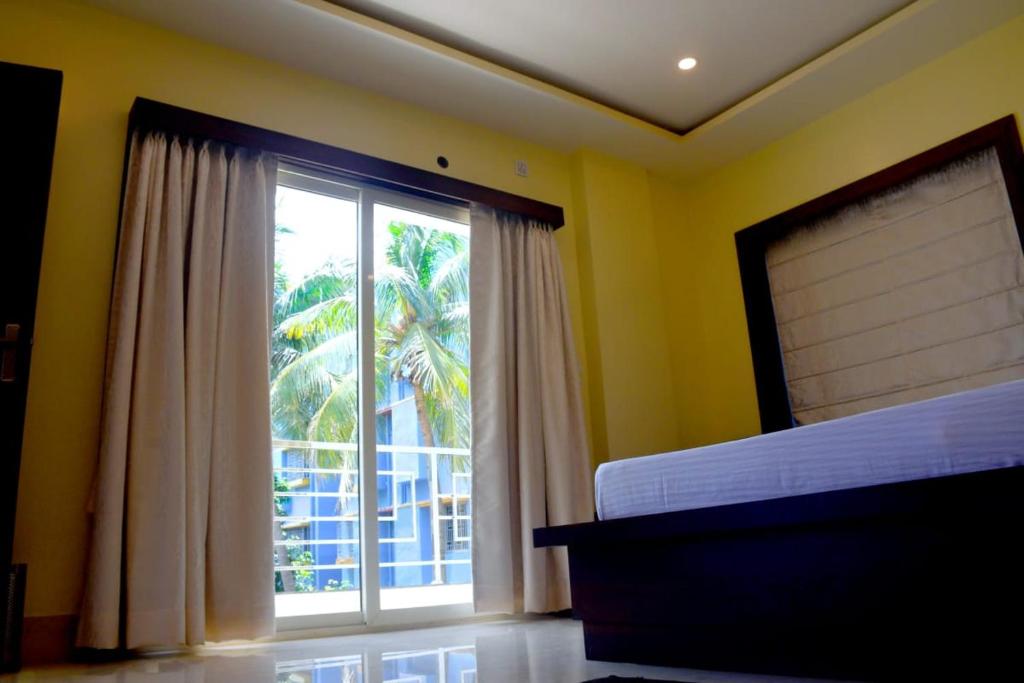 a bedroom with a large window with a view of a palm tree at PRINCE PALACE in Jhārgrām