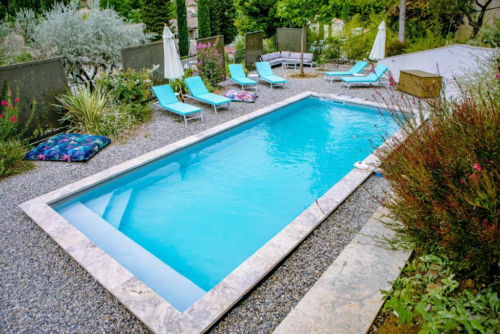 a swimming pool in a garden with blue chairs and sidx sidx sidx at Manoir d&#39;Amaury - Chambres d&#39;hôtes in Gréoux-les-Bains
