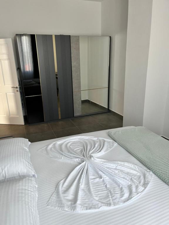 Una cama blanca en una habitación con un espejo grande. en Solen Apartments en Durrës