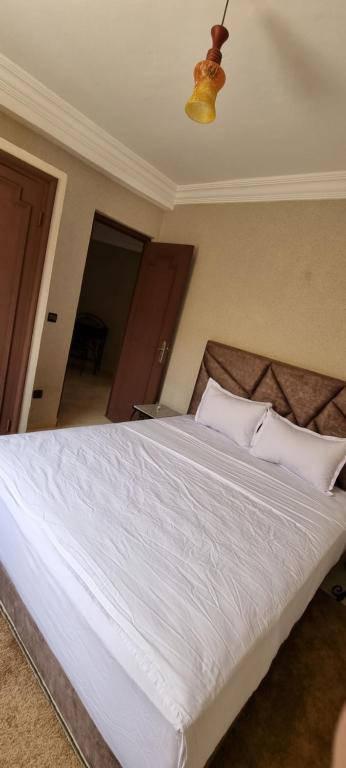 1 dormitorio con 1 cama grande con sábanas y almohadas blancas en Hotel Beach Club la Perle en El Jadida