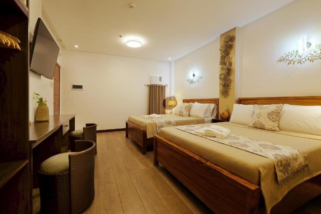 コロンにあるJai-cob’s Suitesのベッド2台とテレビが備わるホテルルームです。