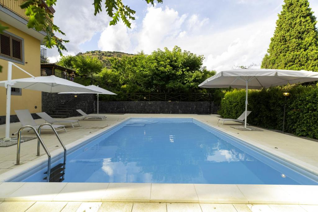una piscina con 2 sombrillas y una casa en Villa Sara sull'etna con Piscina, en Viagrande