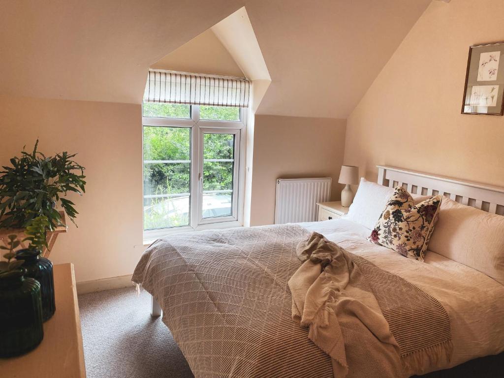 a bedroom with a large bed and a window at Boutique country hideaway ‘Jacks Cottage’ in Diddlebury