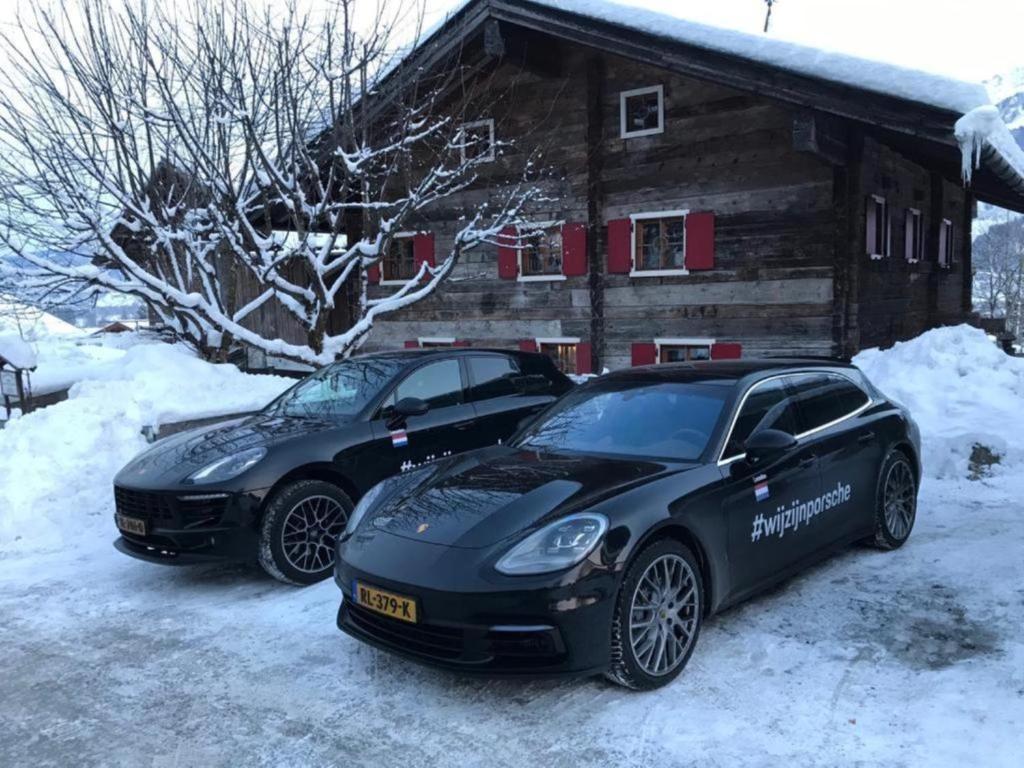 dos autos estacionados en la nieve frente a una cabaña en Das Schmiedhaus, en Kaprun