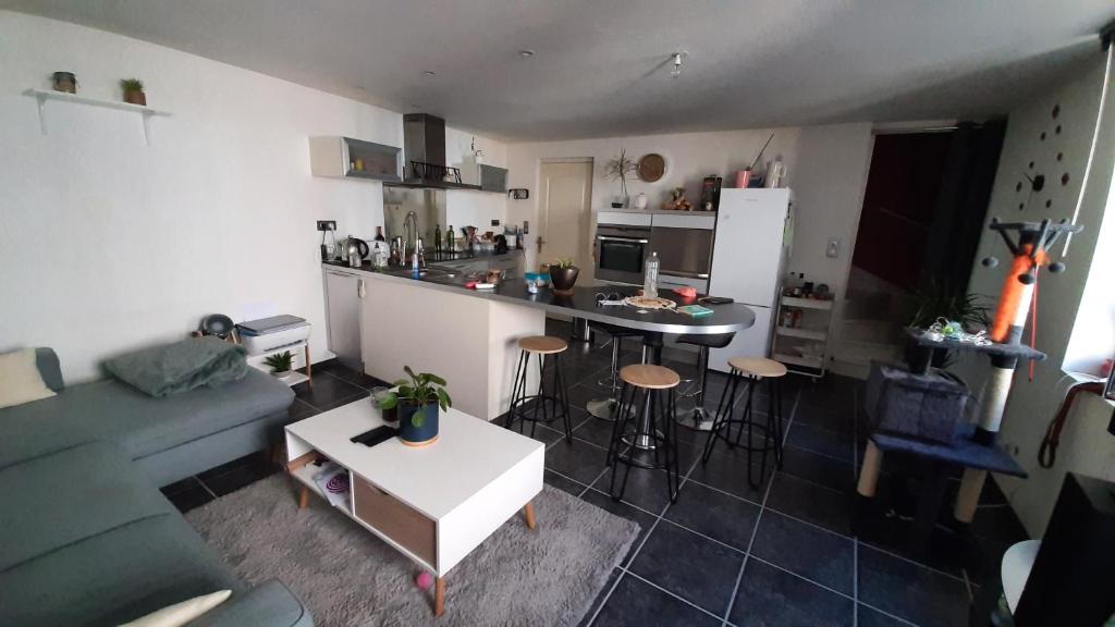 un petit salon avec un canapé et une cuisine dans l'établissement Agréable maison de village, au calme d'une impasse, à Aubière