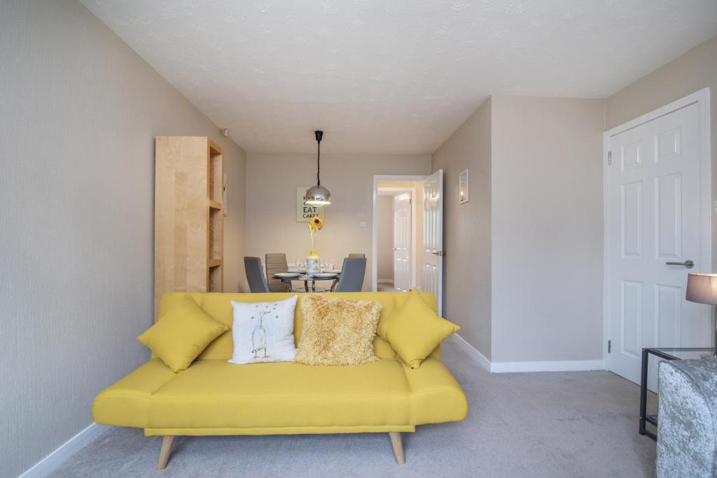 a living room with a yellow couch with pillows at The Kelvin - Peaceful West End River View Property in Glasgow
