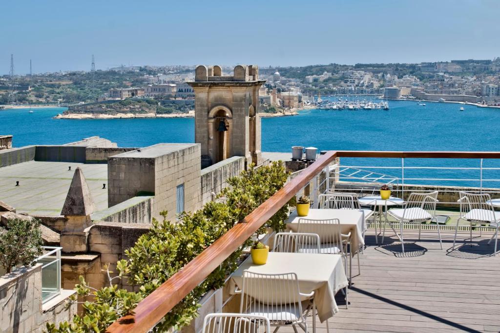 einen Balkon mit Tischen und Stühlen und Blick auf das Wasser in der Unterkunft Ursulino Valletta in Valletta