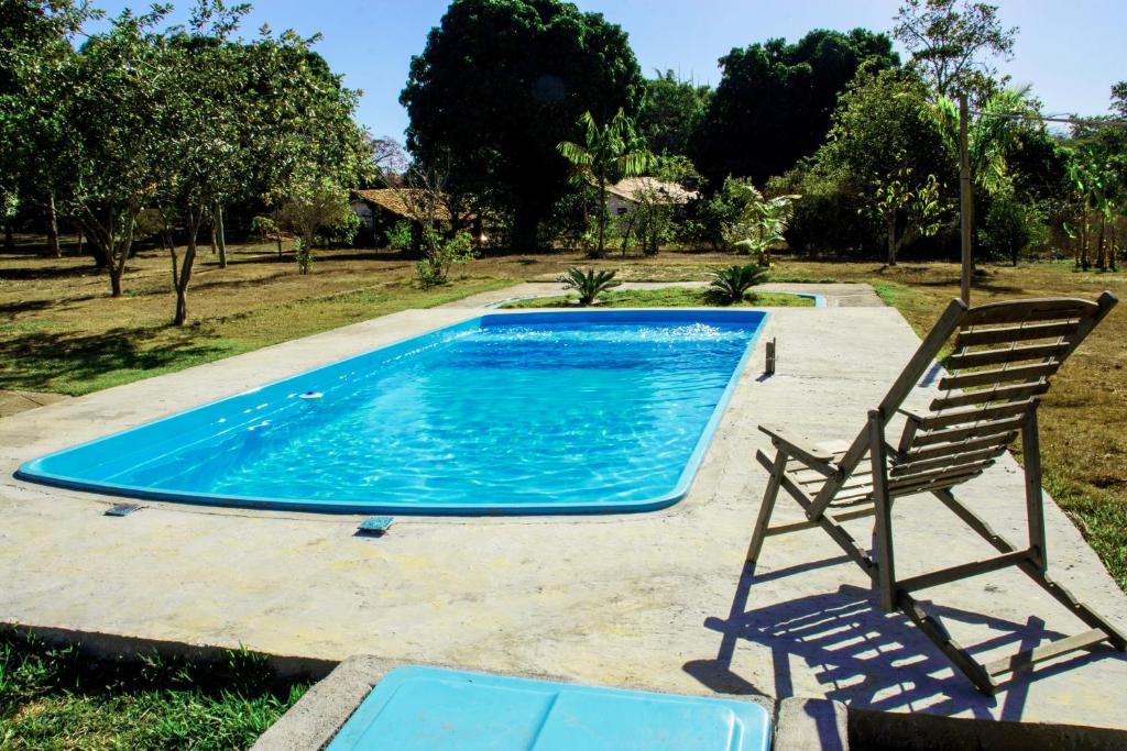 una piscina con 2 sillas y una silla junto a ella en Fazenda Com Piscina e Churrasqueira Curvelo, en Curvelo