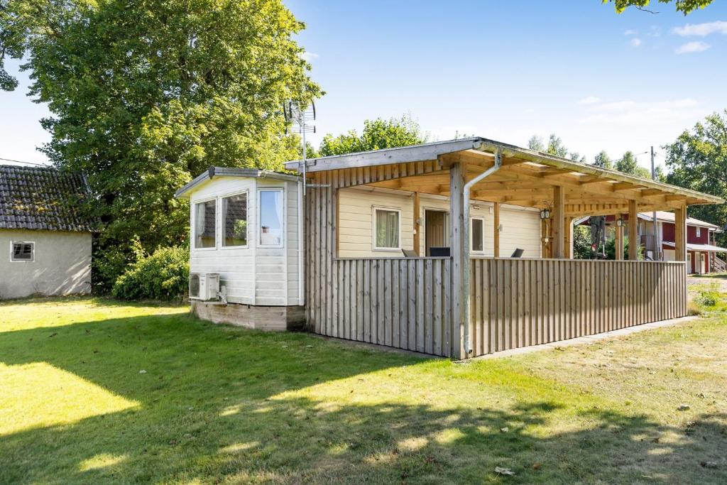 una pequeña casa con una valla en un patio en Mobile home in Sjöared, en Markaryd