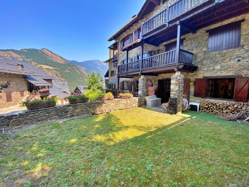 un edificio con un patio de césped delante de él en Pleta de Ordino 55 Casa Rústica hasta 6 personas, en Ordino