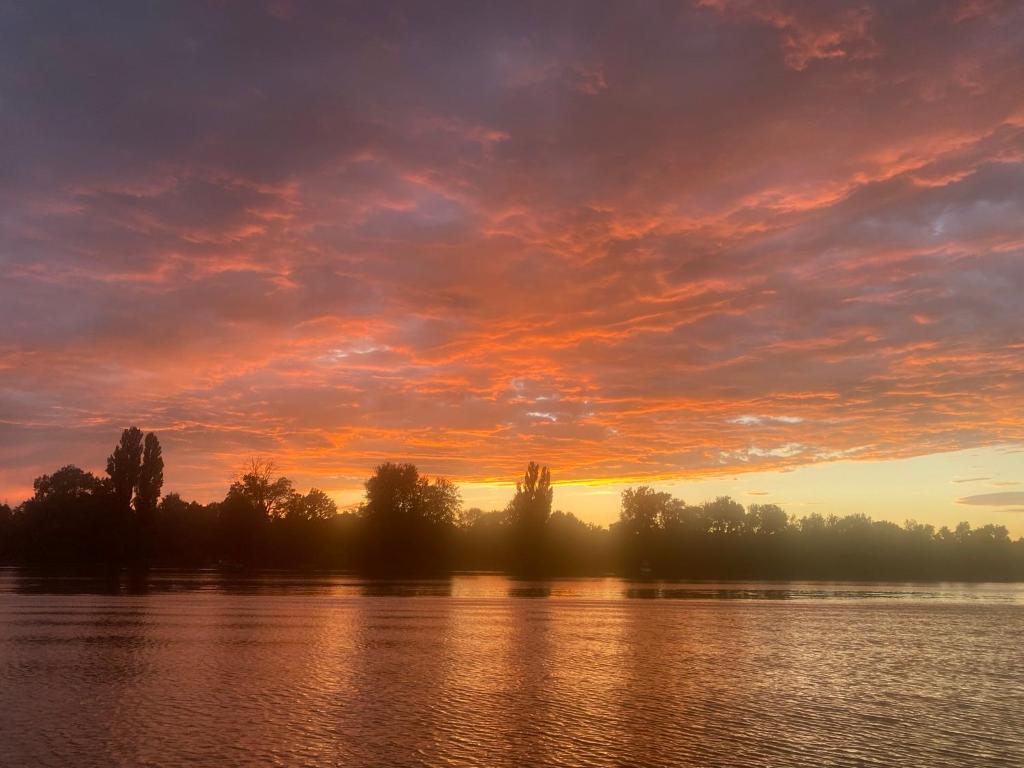 una puesta de sol sobre un lago con árboles en el fondo en Icuka vendèghàza, en Kiskunlacháza