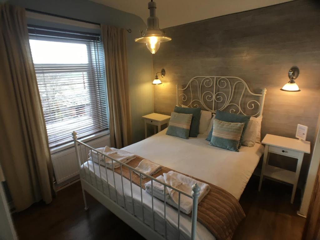 a bedroom with a bed with a white bed frame and a window at Ty Rosa Rooms in Cardiff
