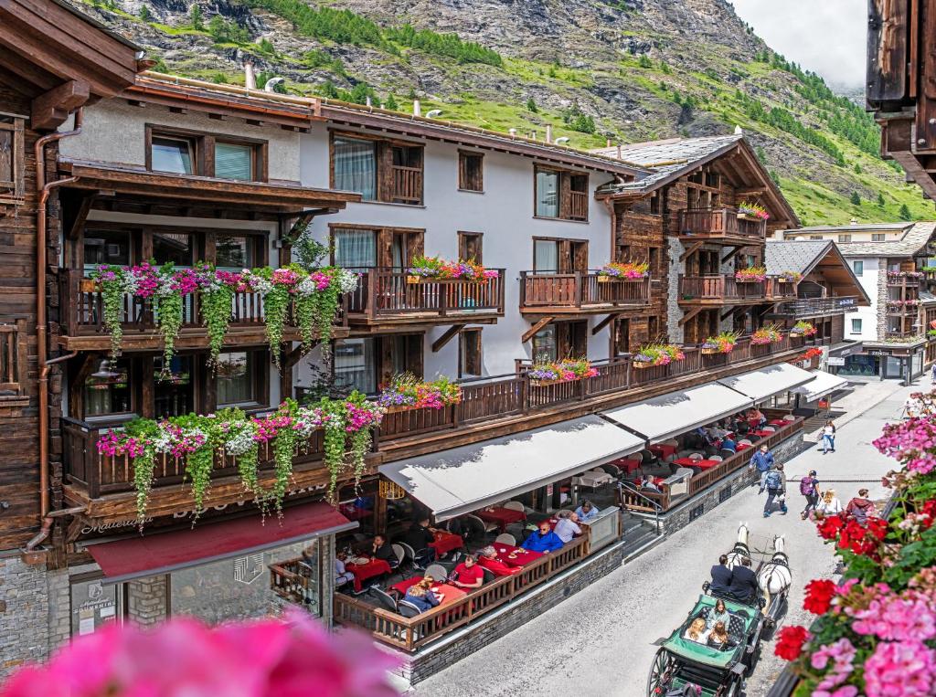 an old town with a horse drawn carriage in front of buildings at Hotel Derby in Zermatt