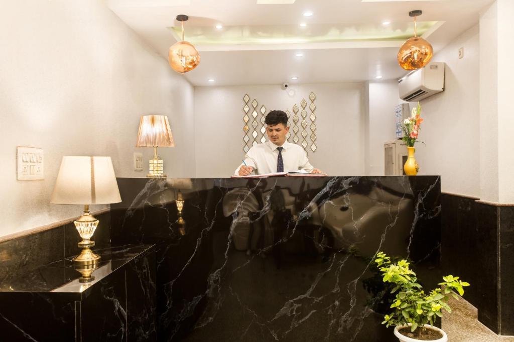 a man standing behind a counter in a hotel lobby at Hotel Earth in New Delhi