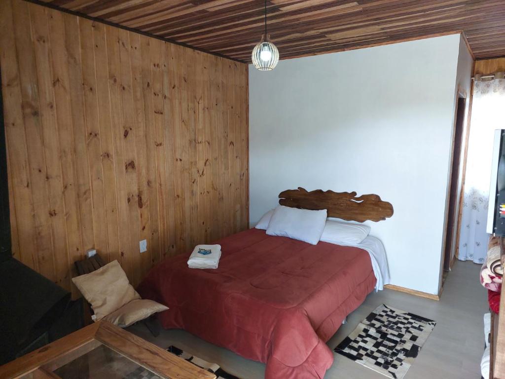 a bedroom with a bed in a room with wooden walls at Portal dos Cânions Pousada in Cambará