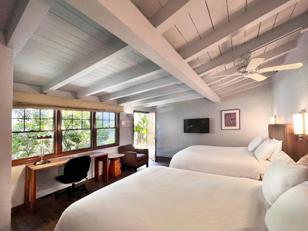 a bedroom with two beds and a desk and a tv at Casa Del Mar Inn in Santa Barbara